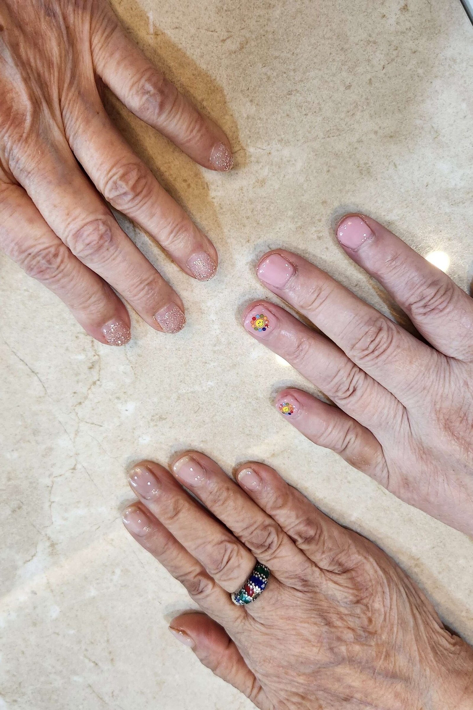 Three aged hands, one with gold dot accent, sheer nude for women over 60 - simple clear nail idea 26