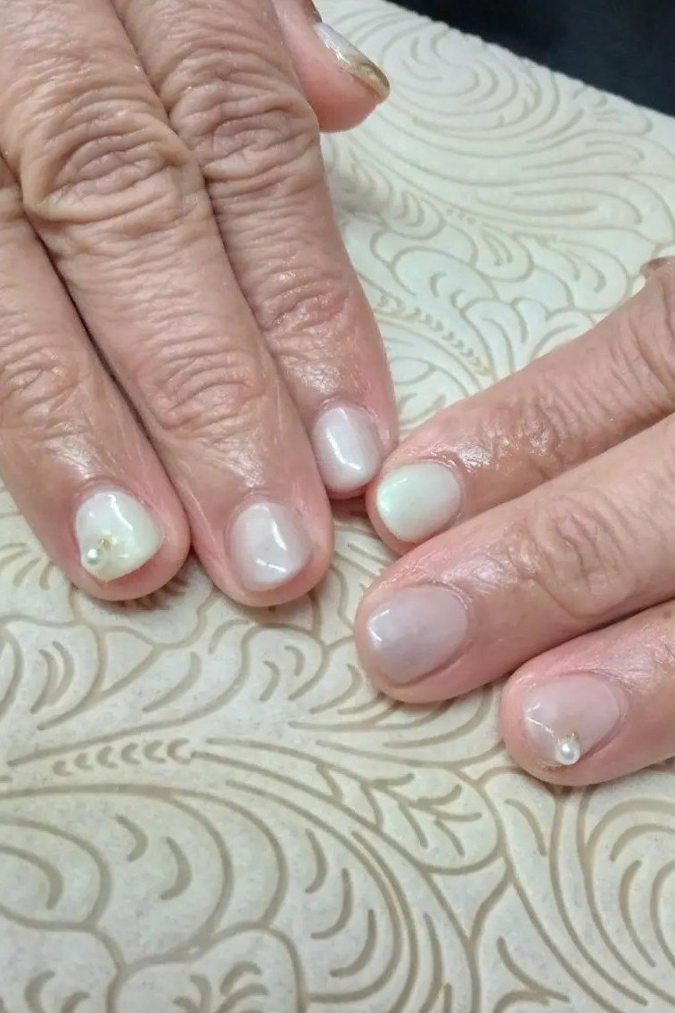 Milky white nails with pearl accent nail on older hands