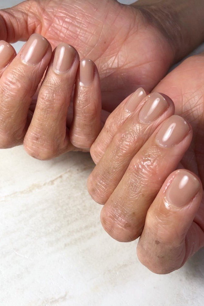 Nude glossy nails on mature hands