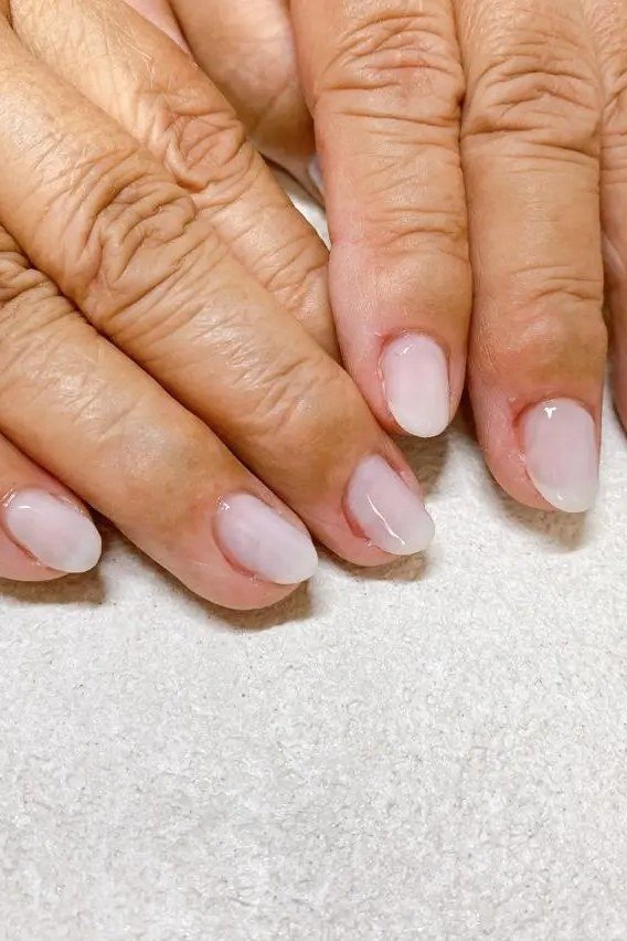 Pale pink cream polish on mature hands