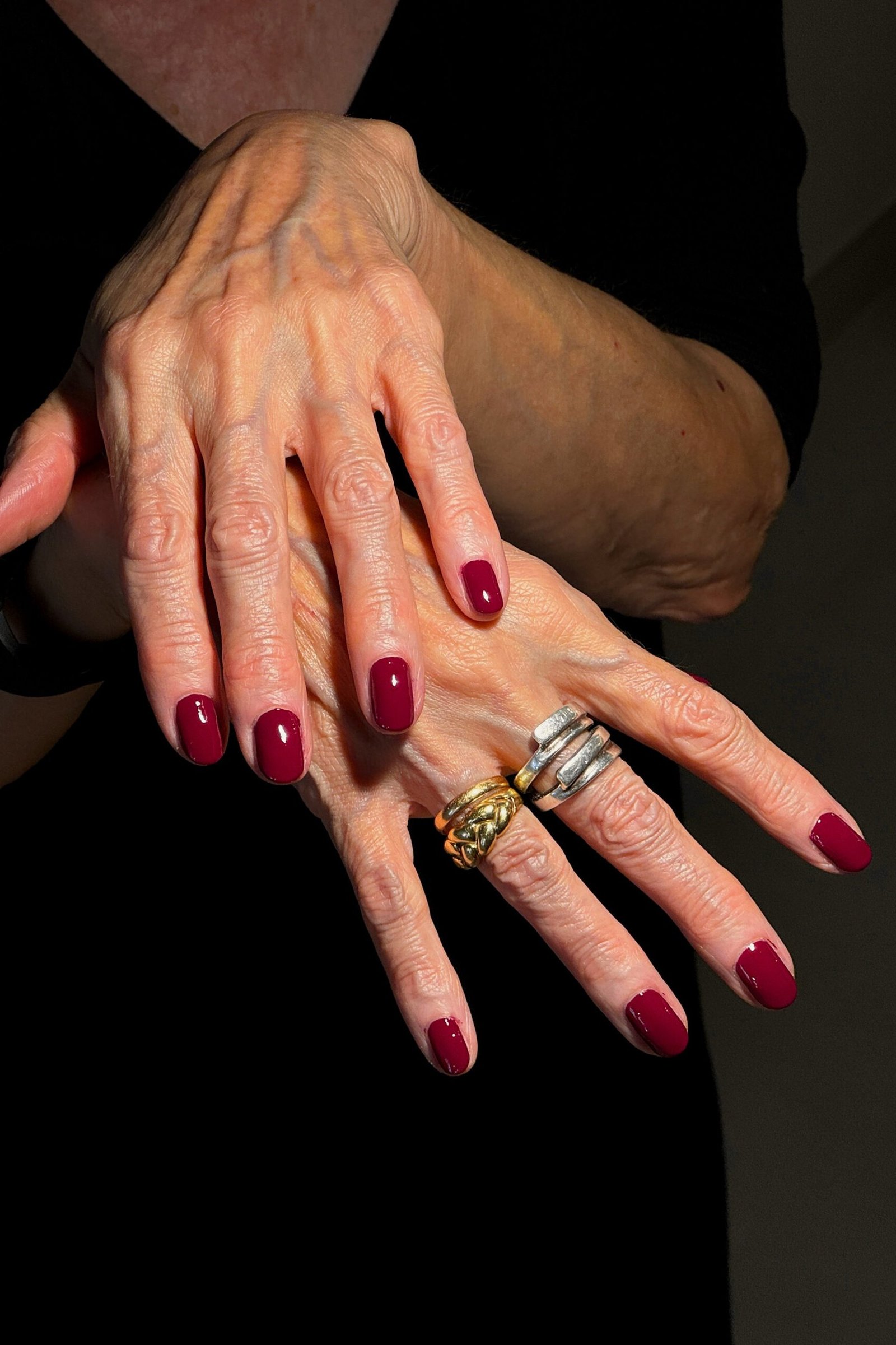 Party-ready red nails with stacked silver rings for women over 60