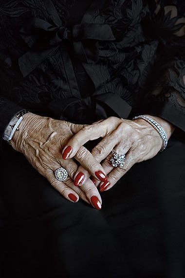 Classic red manicure on clasped hands with bracelets for women over 60