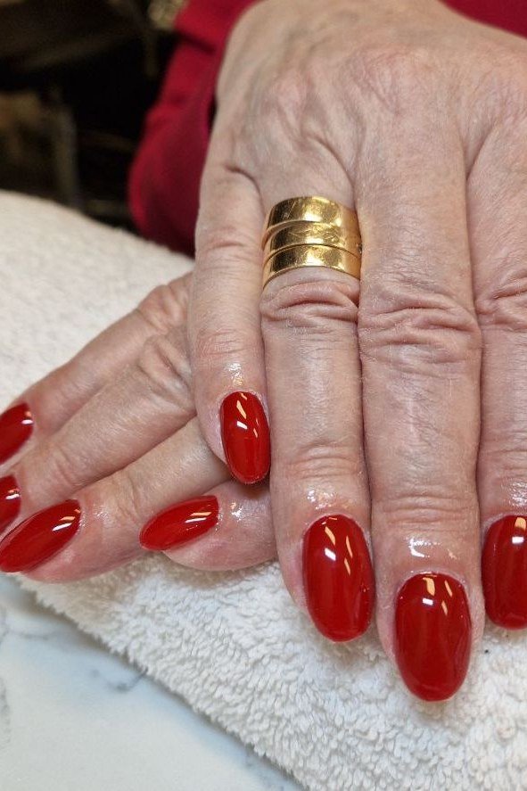 Bright red oval nails fresh salon on white towel for women over 60