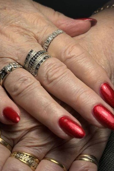 Molten metallic red manicure with mixed rings for women over 60
