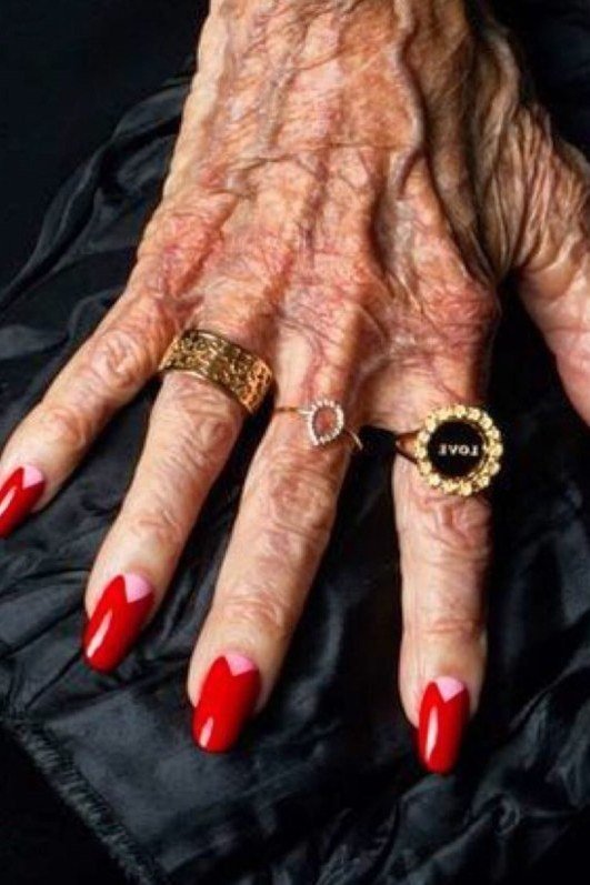 Classic red manicure with heirloom gold rings for women over 60