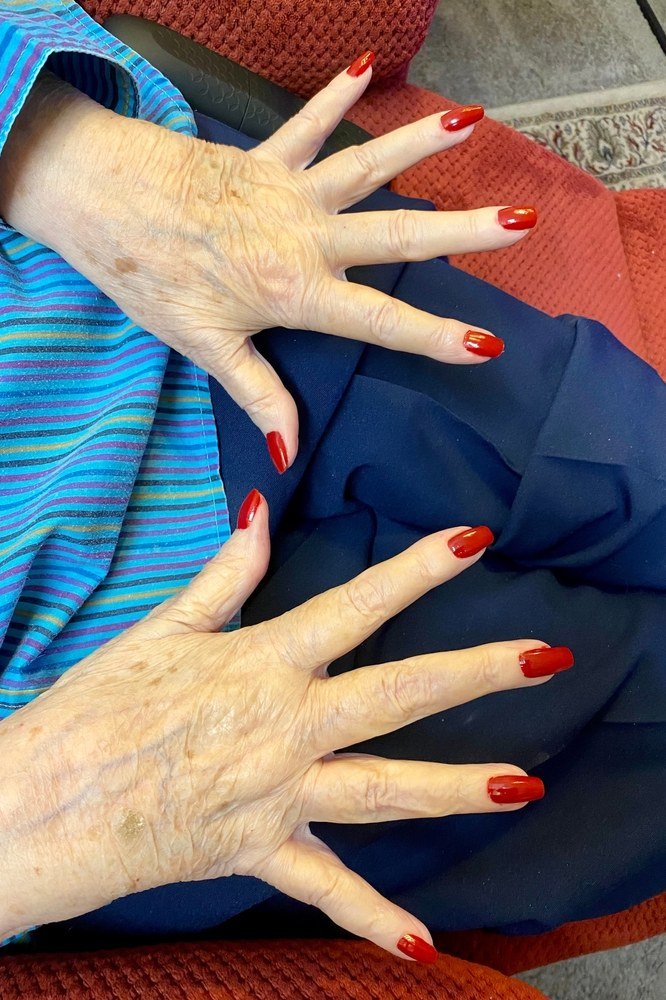 Bright red nails over blue striped top for women over 60