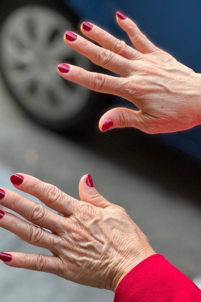 Bright red manicure outdoors on the go for women over 60