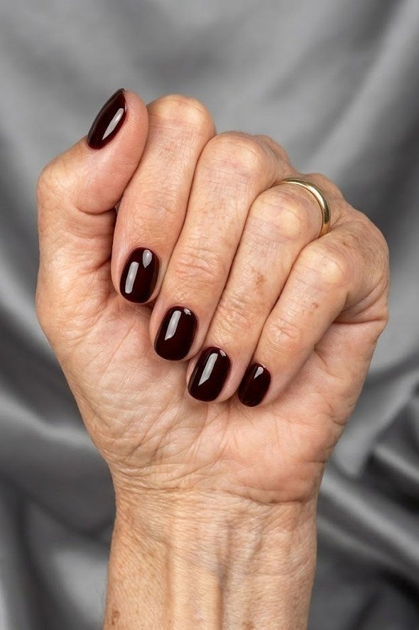 Near-black oxblood red glossy nails for women over 60