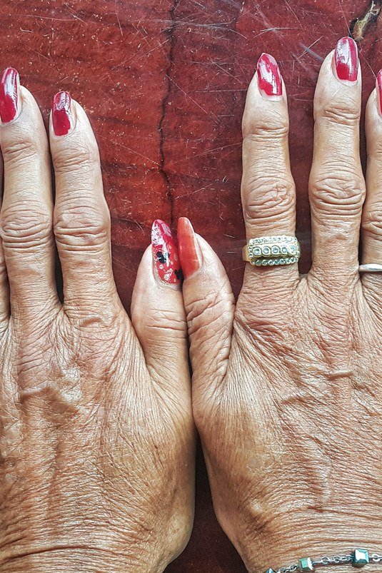 Deep red manicure tone-on-tone with red fabric for women over 60