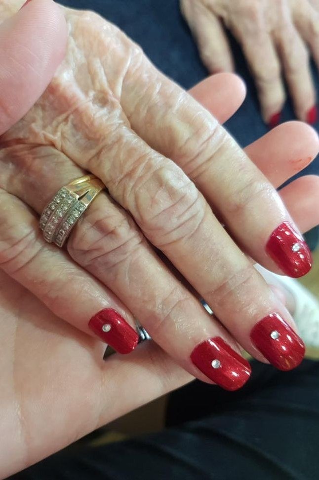 Classic red manicure with delicate ring stack for women over 60