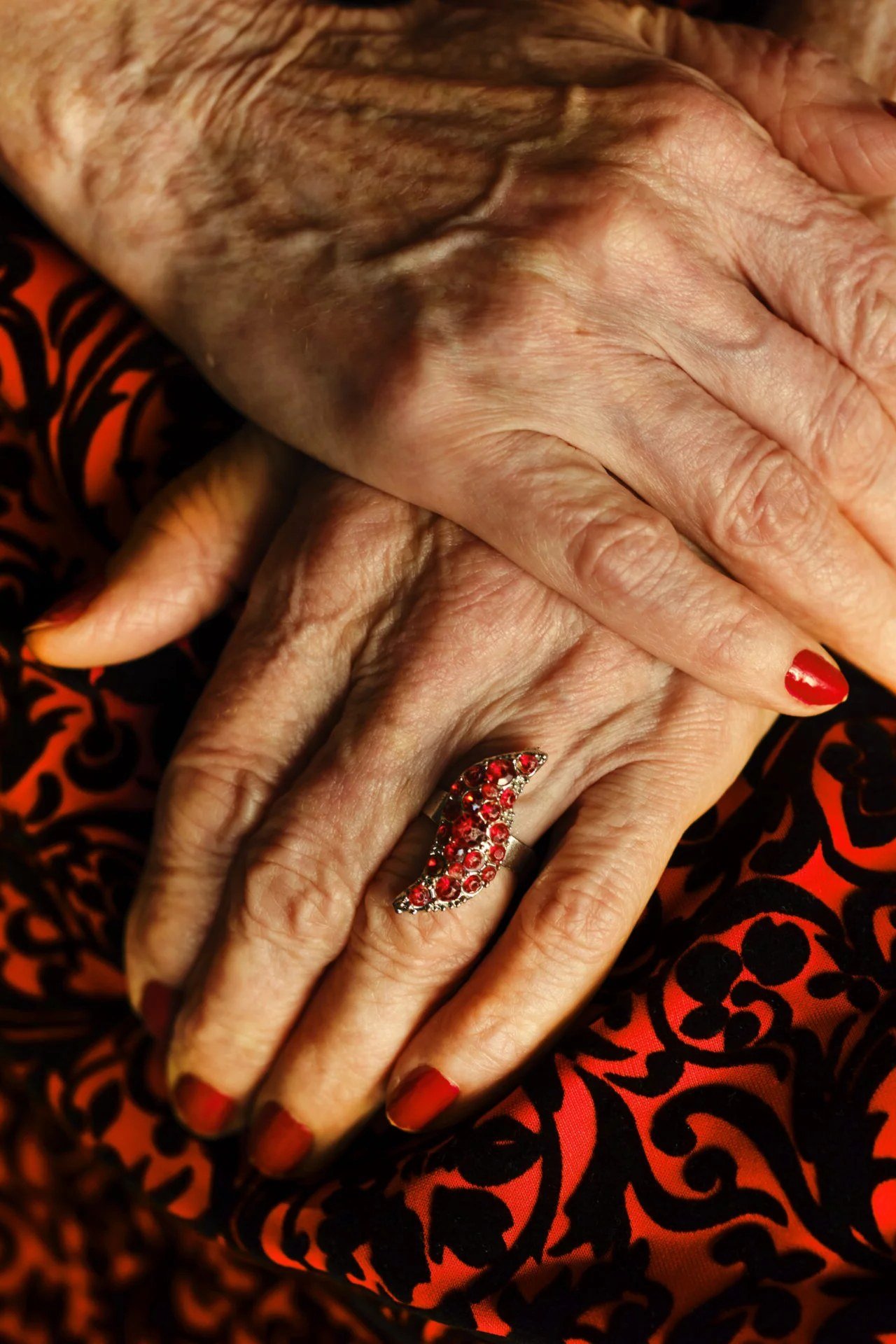 Deep red nails with ruby ring for women over 60