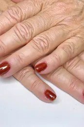 Copper shimmer red manicure crossed hands for women over 60