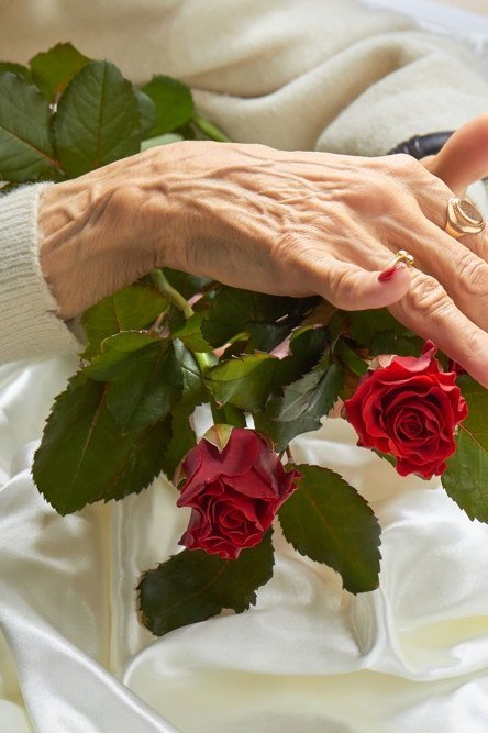 Classic red nails touching red roses for women over 60