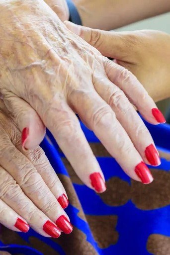 Vivid red oval nails against blue garment for women over 60