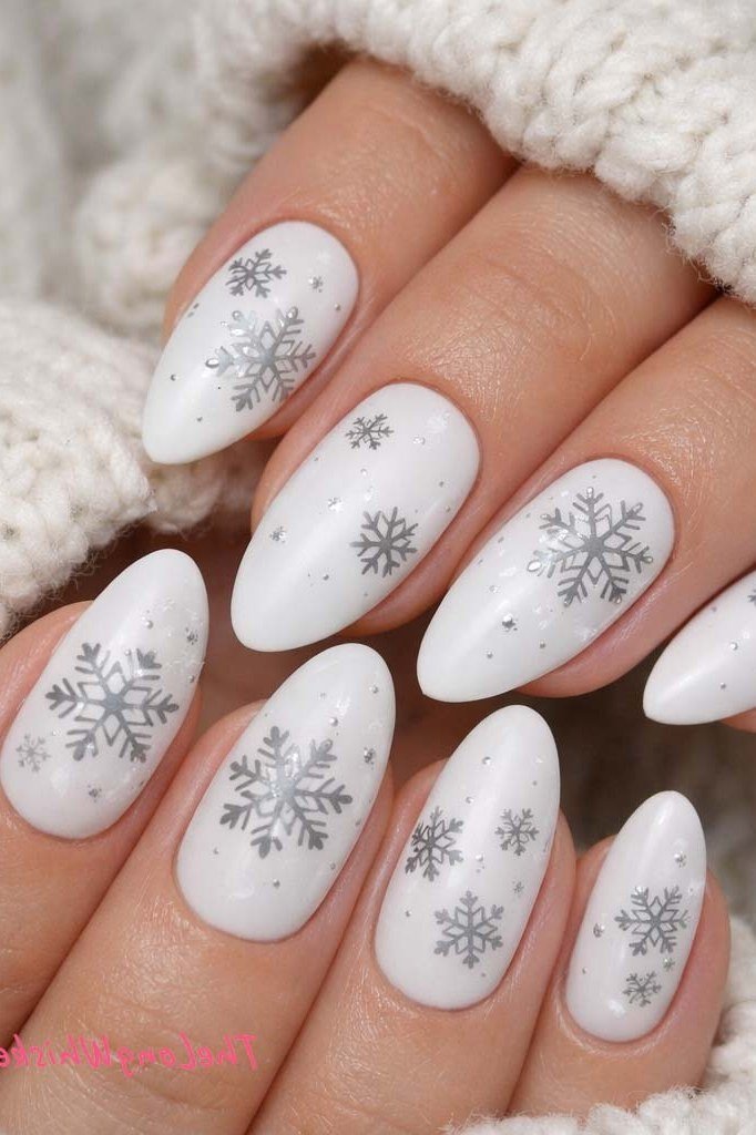 White oval nails with gray snowflake prints, elegant winter manicure