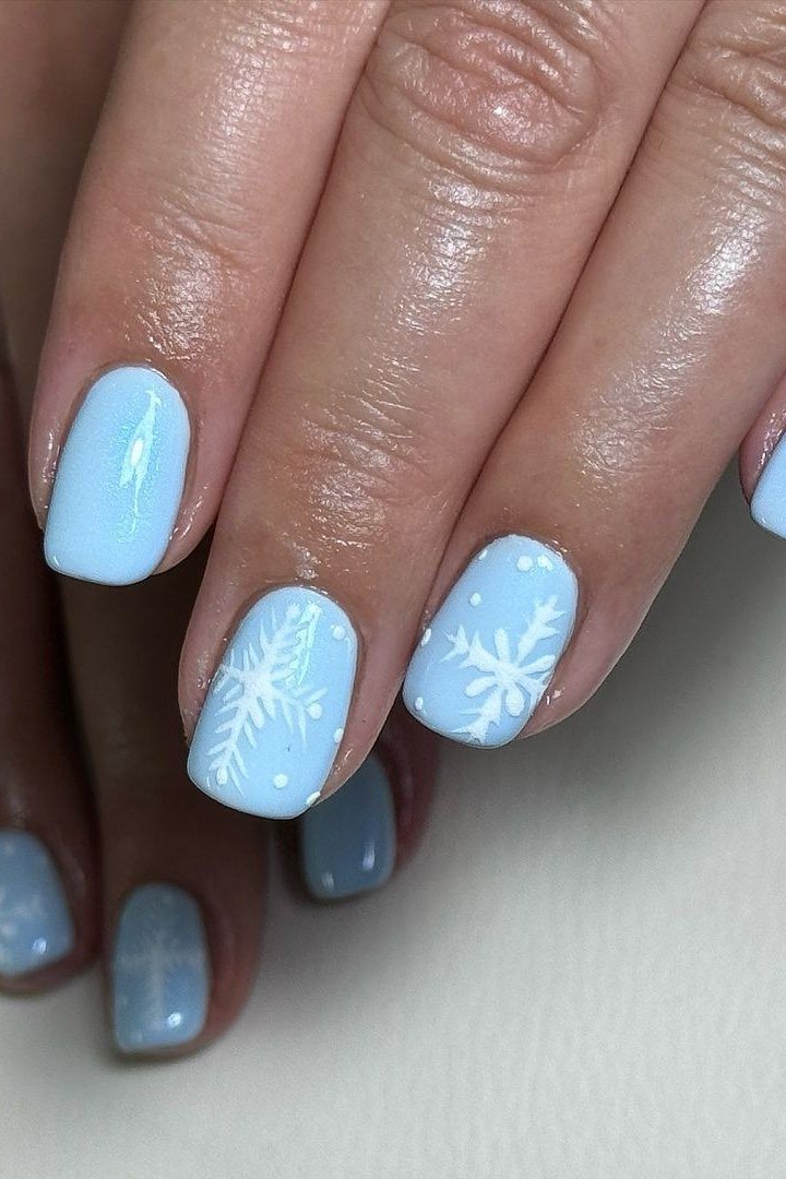 Light blue nails with white snowflake nail art, frosty winter design