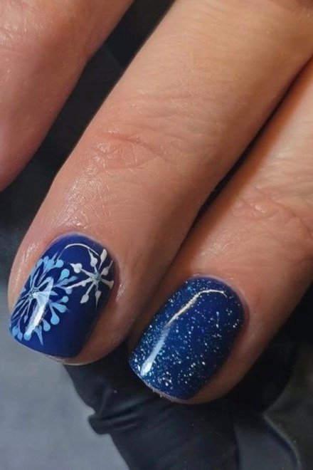 Deep navy nails with bold white snowflakes, short winter manicure