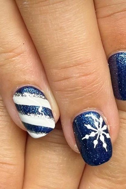Navy nails with white snowflakes and candy stripe accents