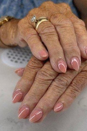 Elegant soft rose-pink nails on very wrinkled older hands for women over 40