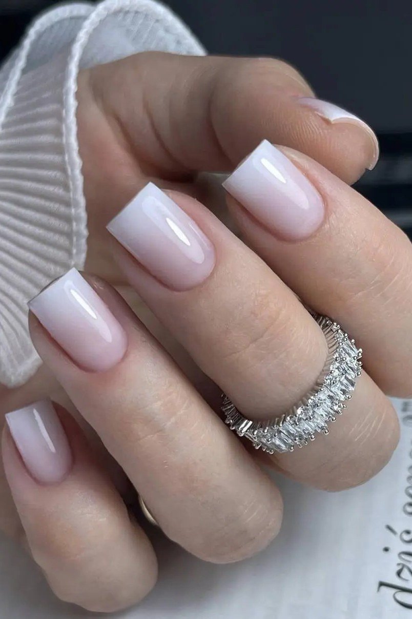Elegant pale pink French tips beside a book, soft and feminine for women over 40