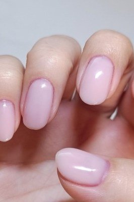 Elegant glossy pink short nails at a desk, everyday look for women over 40