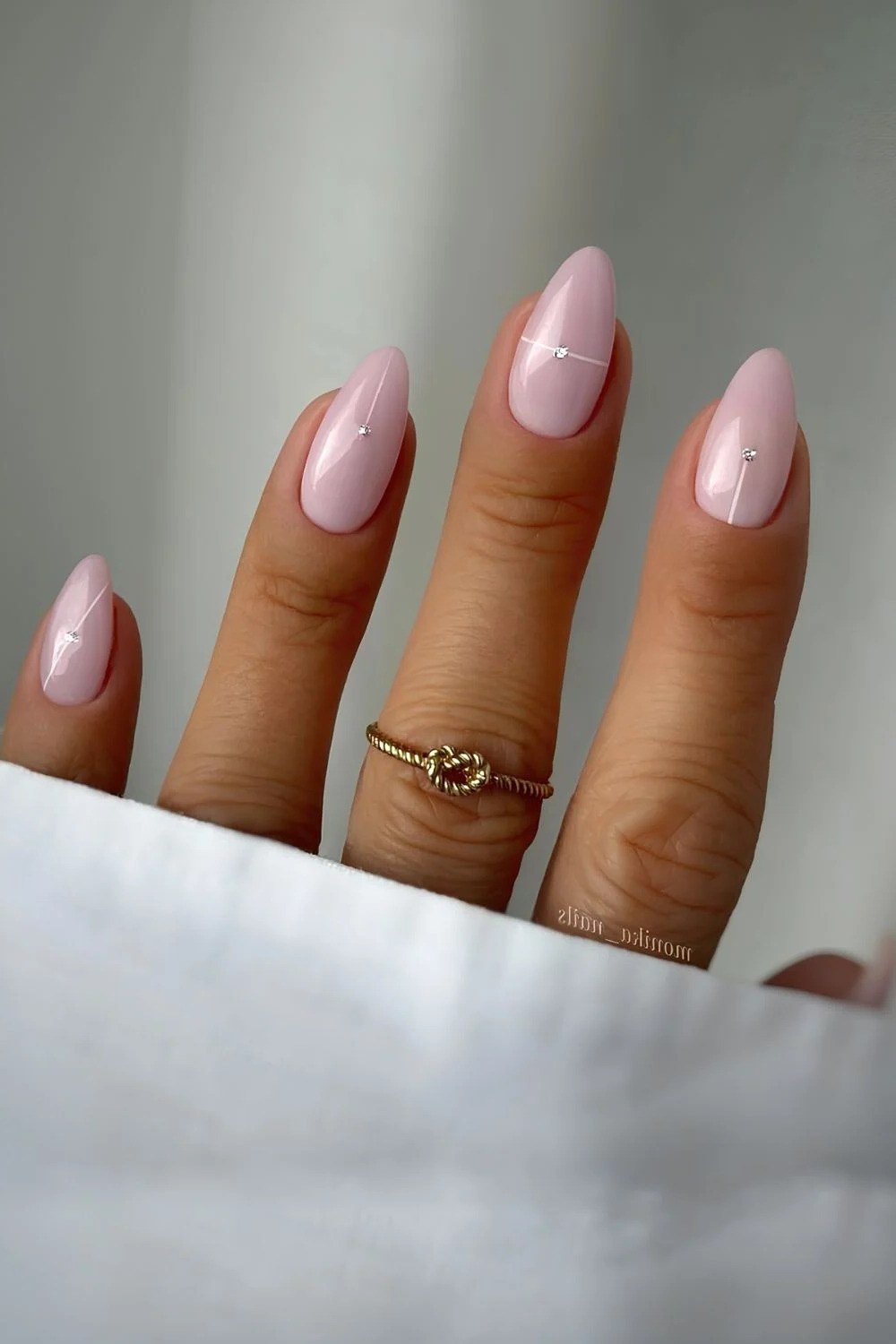 Elegant nude-pink almond nails on brown skin with gold ring for women over 40