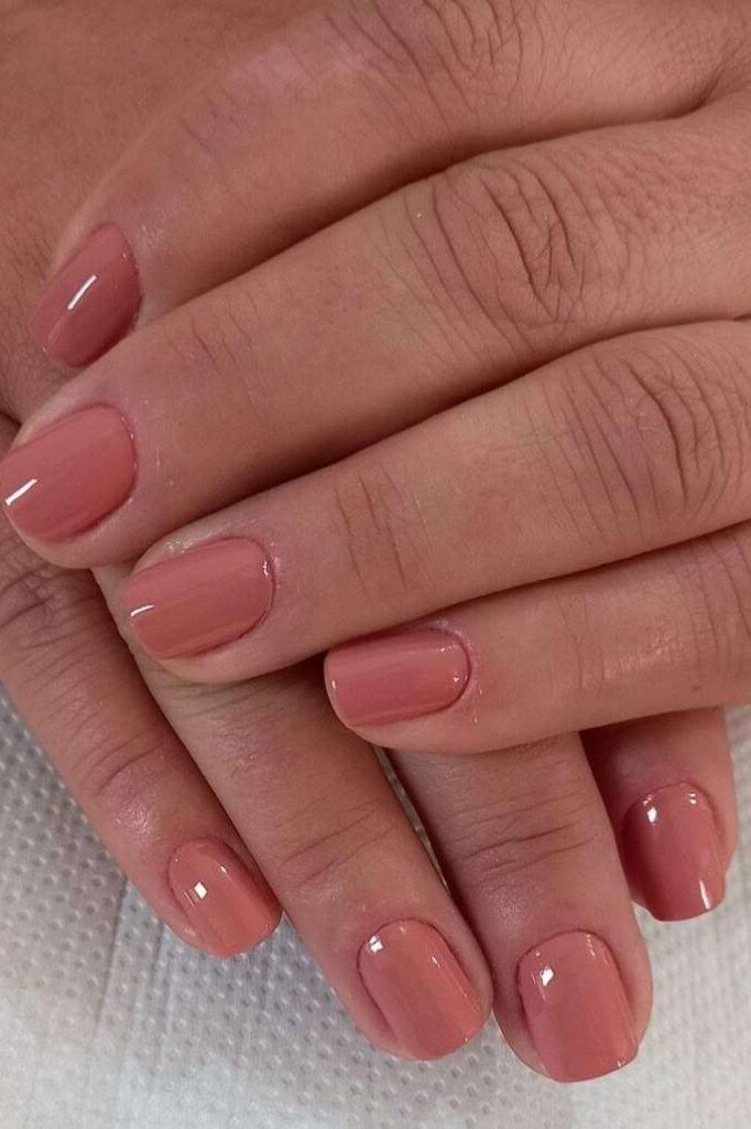 Elegant coral pink glossy square nails on mature hands for women over 40