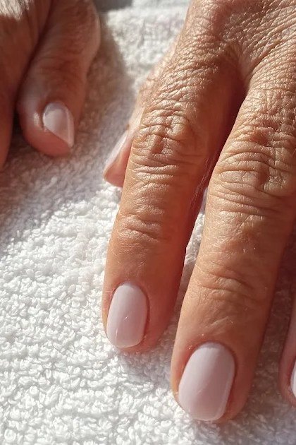 Elegant sheer pale pink nails on thin older hands for women over 40
