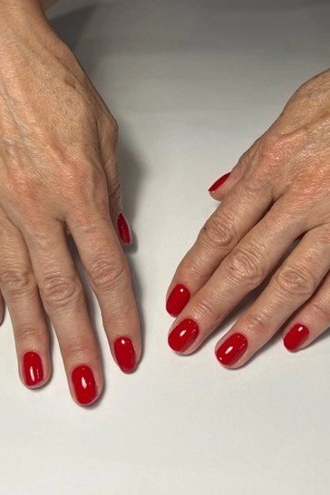 Mature hands with short red oval nails