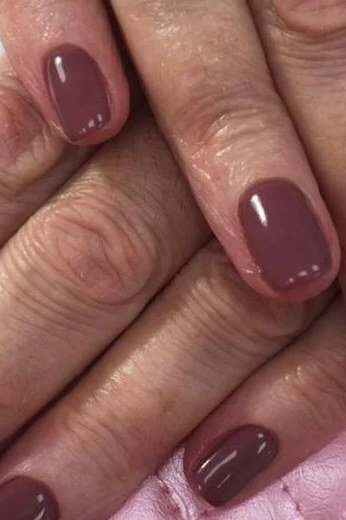 Mature hands with burgundy oval nails and pink quilted bag