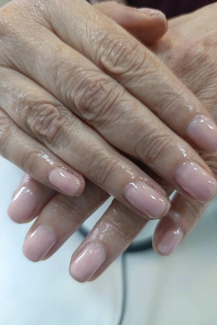 Sheer pink nails, mature wrinkled hands