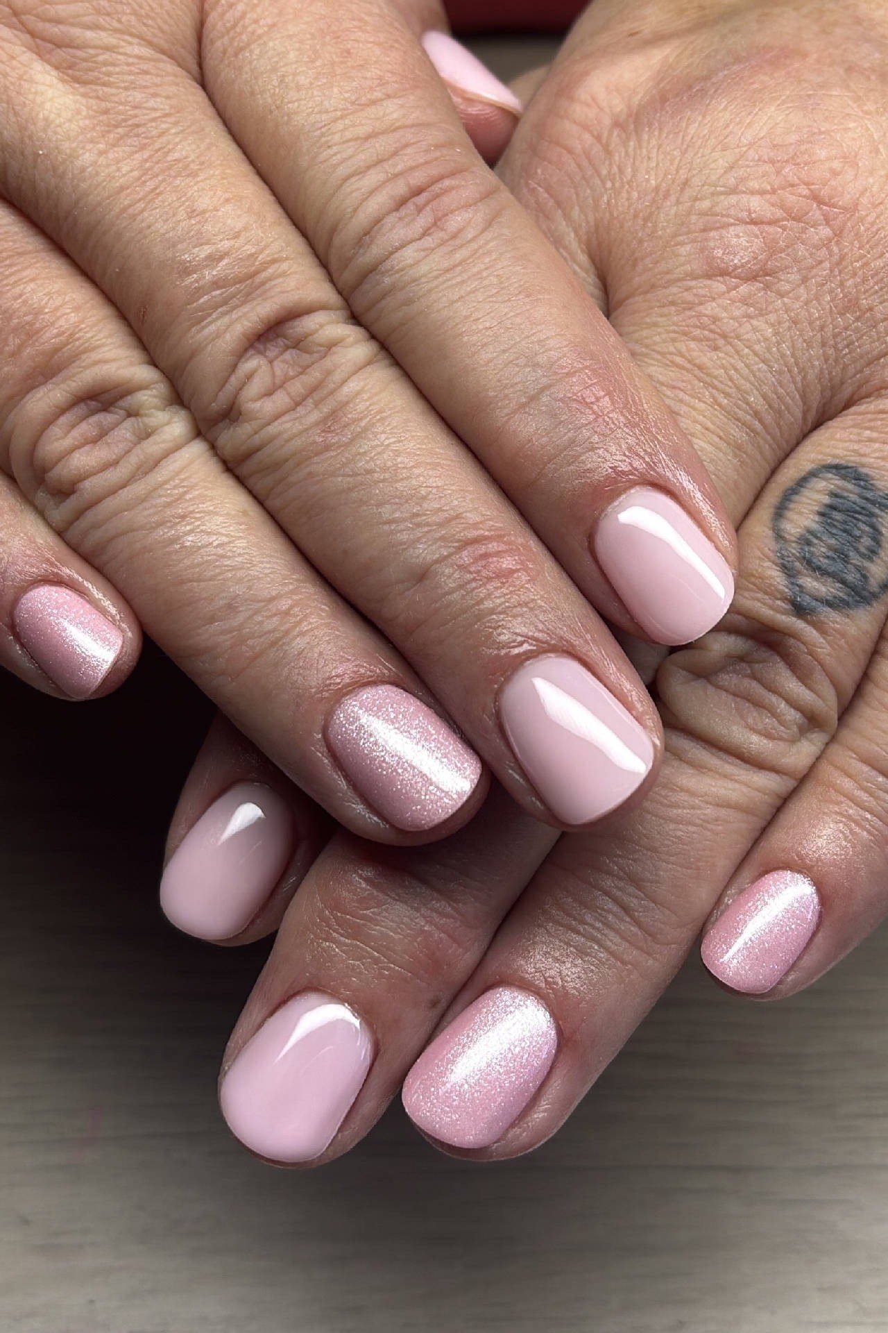 Sheer pink nails, mature hands with wrist tattoo