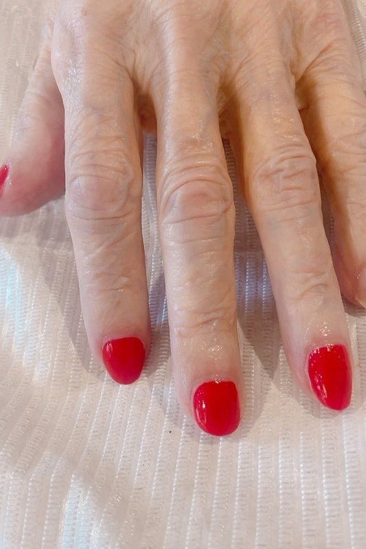 Bright red nails, older hands