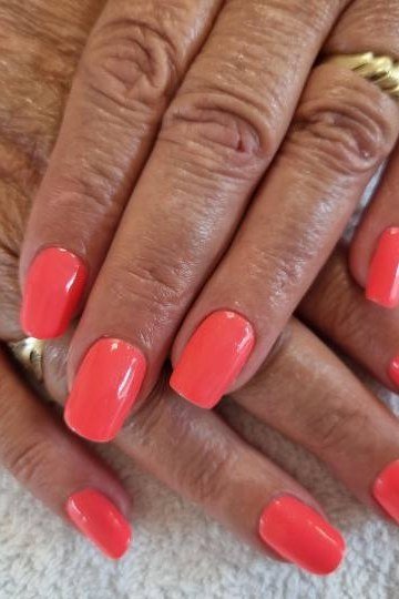 Bright coral nails, mature hands
