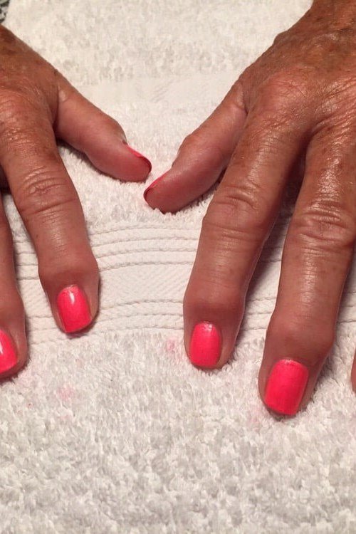 Bright coral nails, mature hands