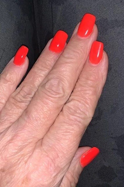 Neon coral nails, older hand