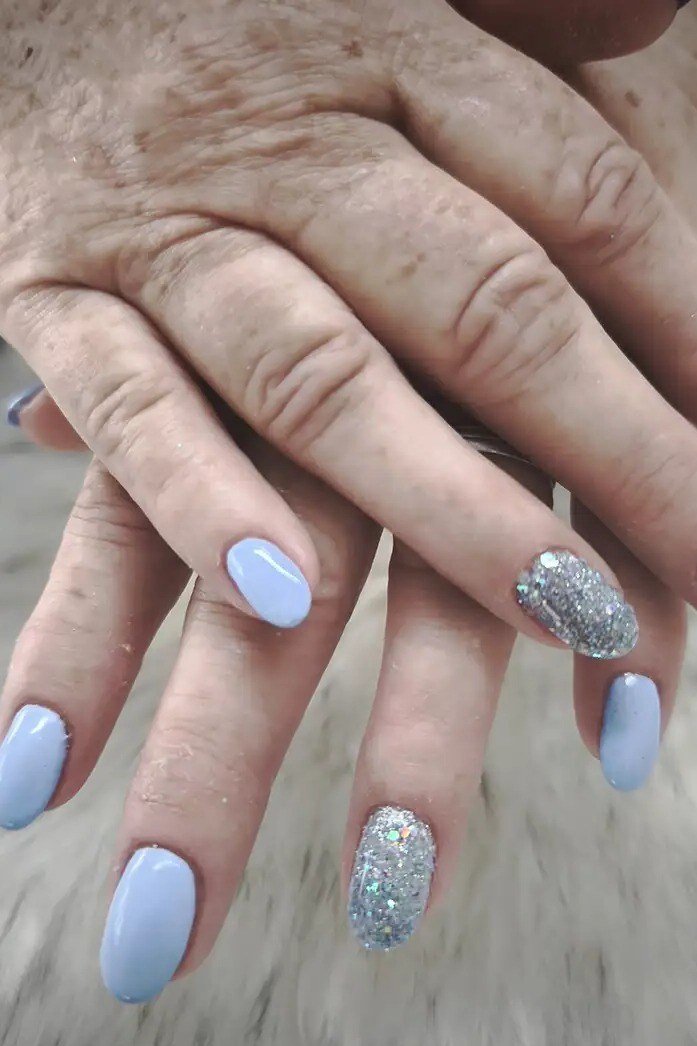 Pale blue nails with silver glitter accent, older hands