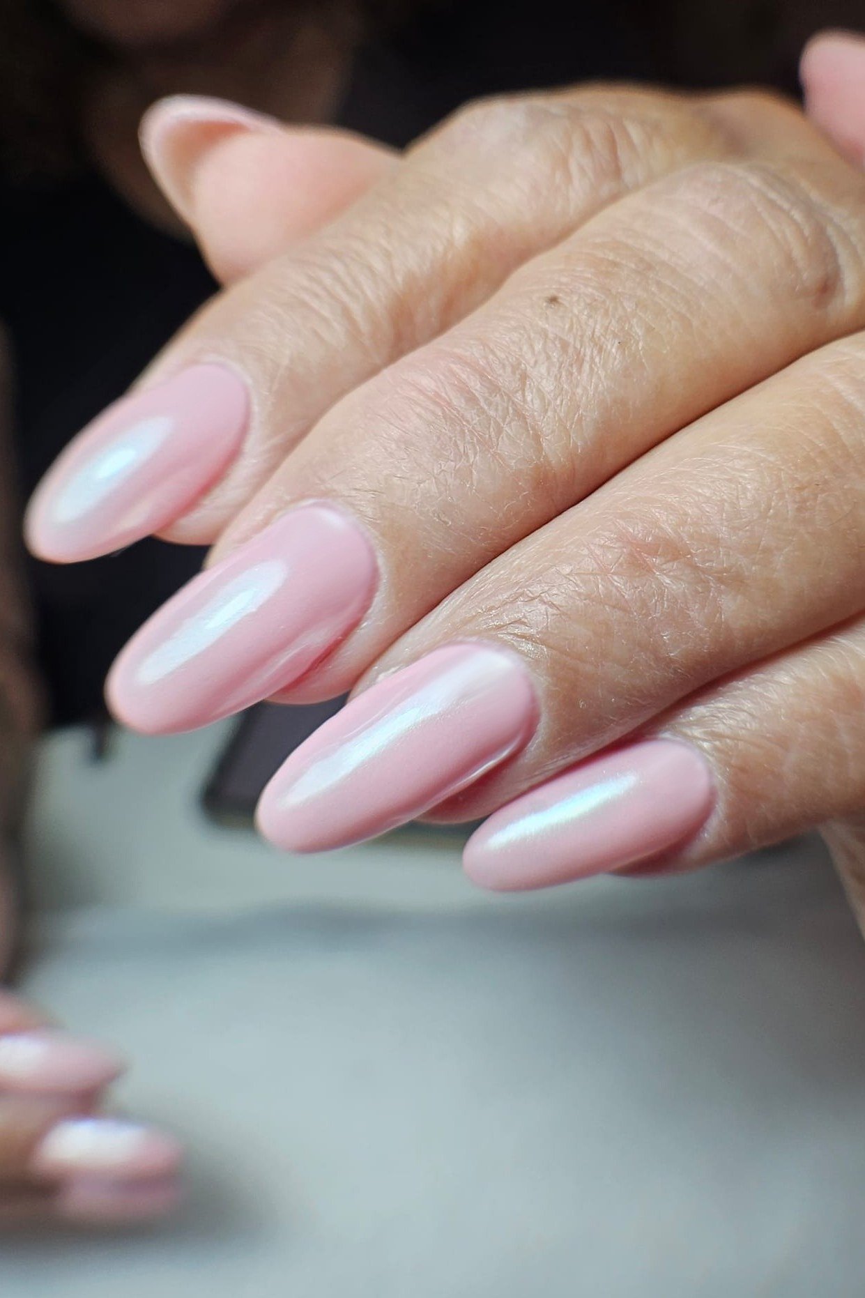 Pink chrome almond nails, mature hands close-up