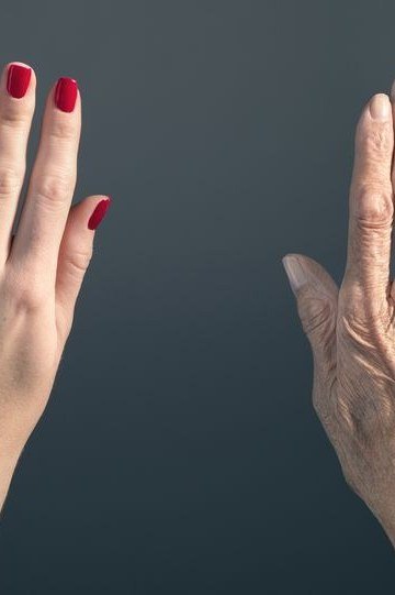 Red round nails, two mature hands on dark background