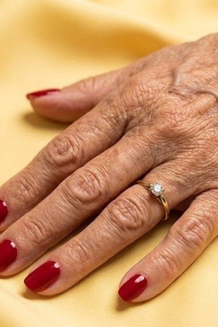 Red square nails, mature hand on yellow fabric