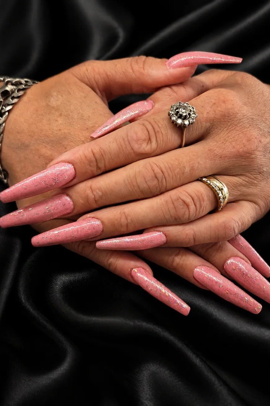 Pink stiletto nails, mature hands on dark background