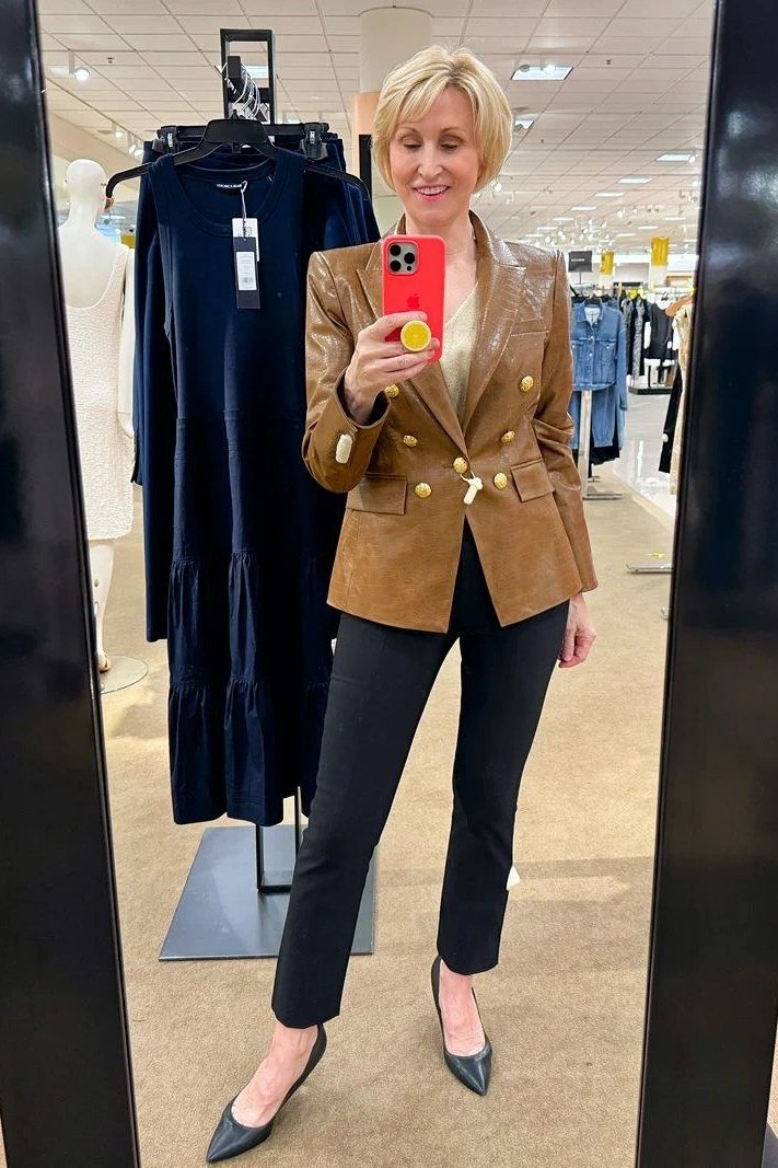Woman over 40 wearing a camel double-breasted blazer with black trousers