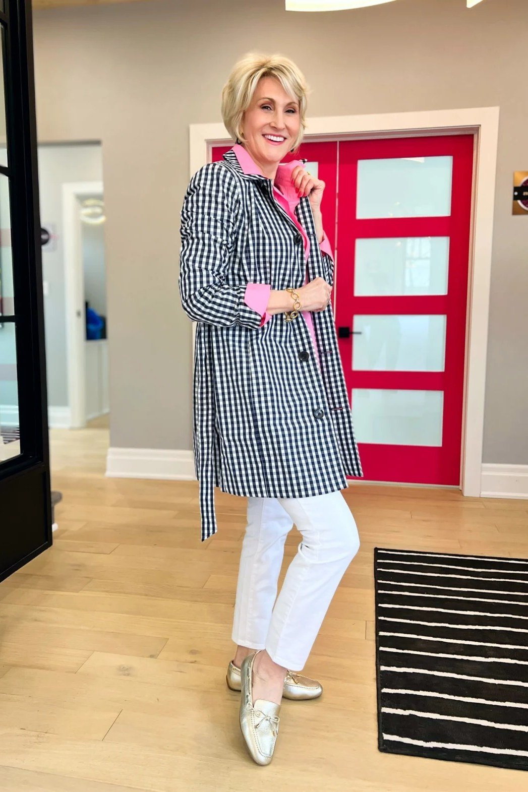Woman over 40 wearing a houndstooth coat with white jeans and metallic flats