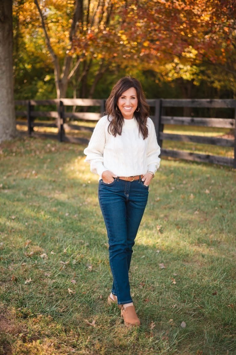 Woman over 40 wearing a white sweater with dark jeans