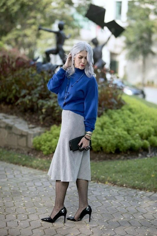 Woman over 40 wearing a cobalt blue top with a gray midi skirt and black heels