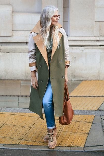 Woman over 40 wearing an olive long vest coat with blue jeans