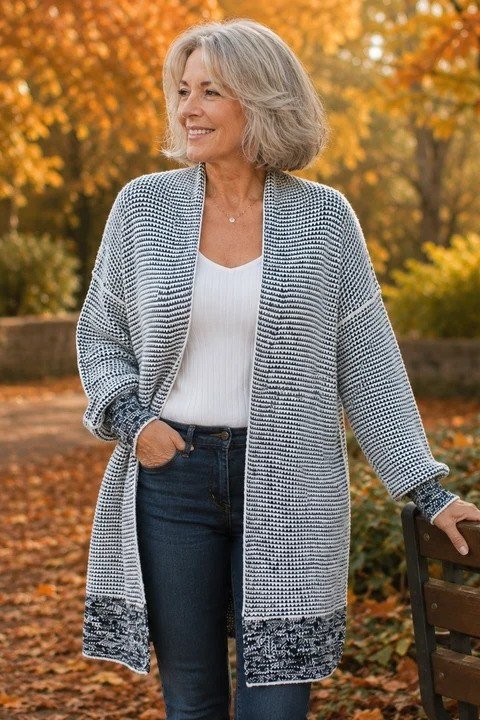 Woman over 40 wearing a long gray cardigan with a white top and jeans