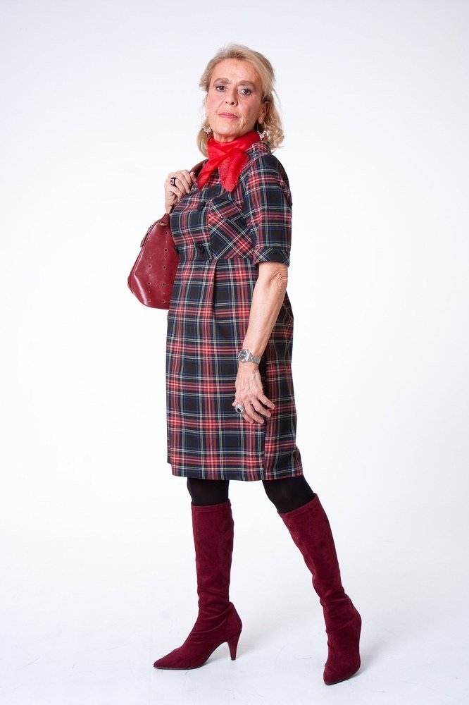 Woman over 40 wearing a red plaid midi dress with red knee boots