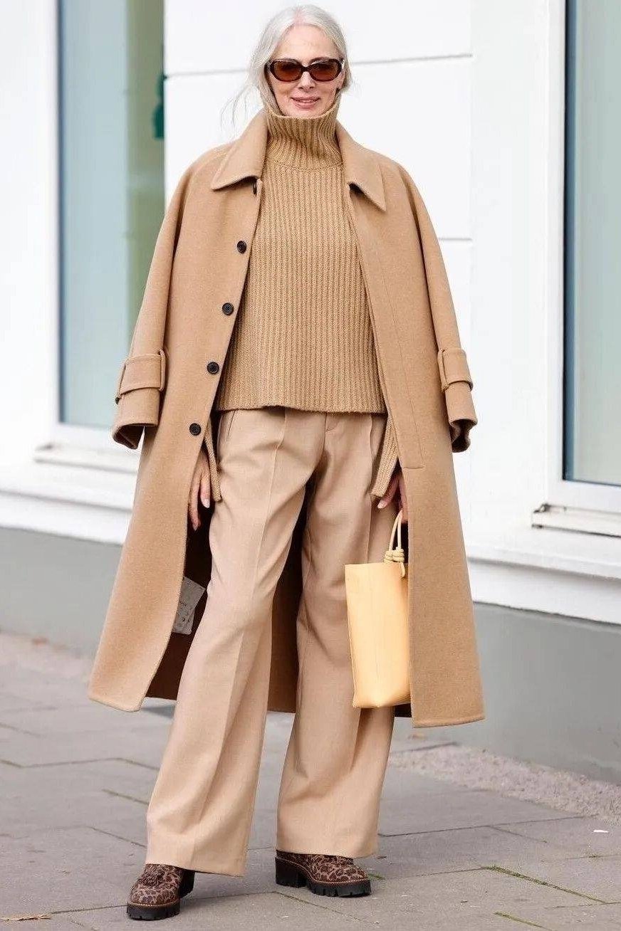 Effortlessly polished outfit for women over 50: A monochrome camel outfit: camel coat, camel knit, camel wide-leg trousers,...