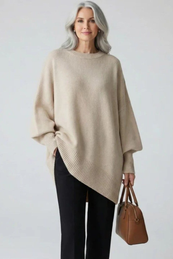 Effortlessly polished outfit for women over 50: An oversized oatmeal knit sweater and black trousers, tan leather tote